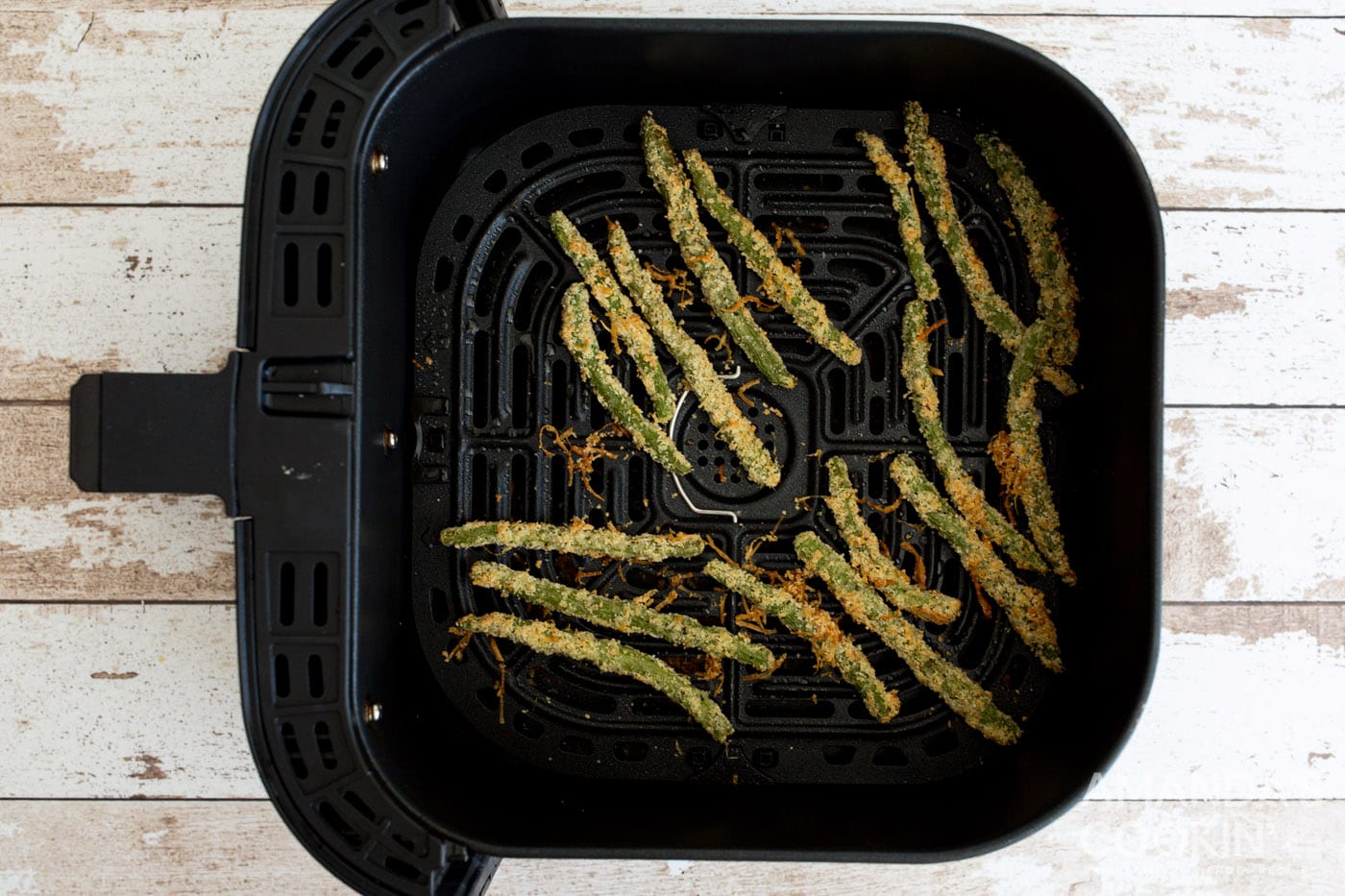 cooked green bean fries in air fryer basket