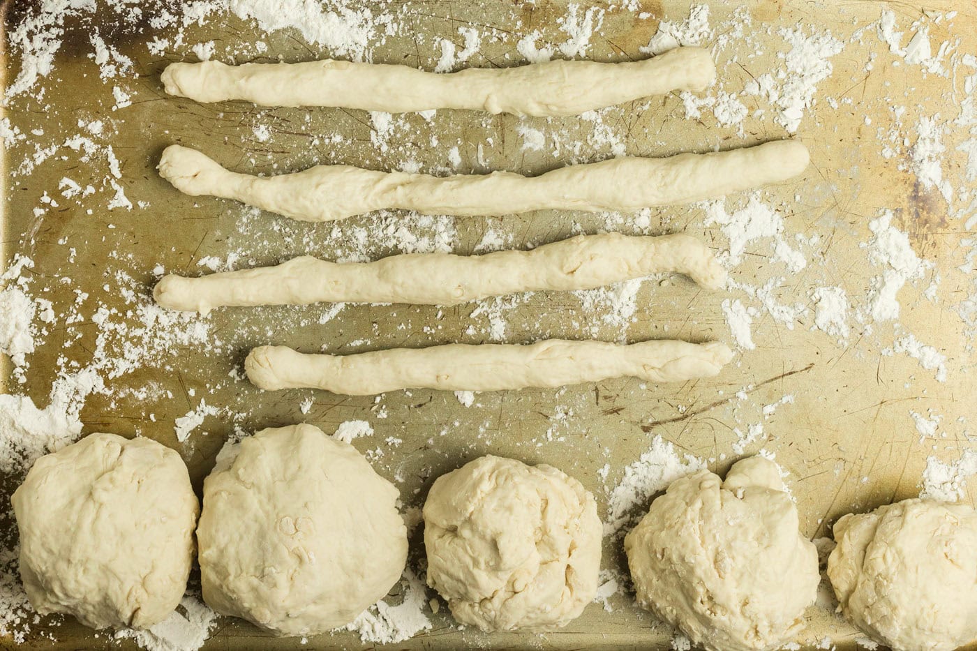 Ropes of dough and dough balls on a floured baking sheet