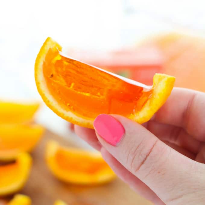 Hand holding orange slice jello shots