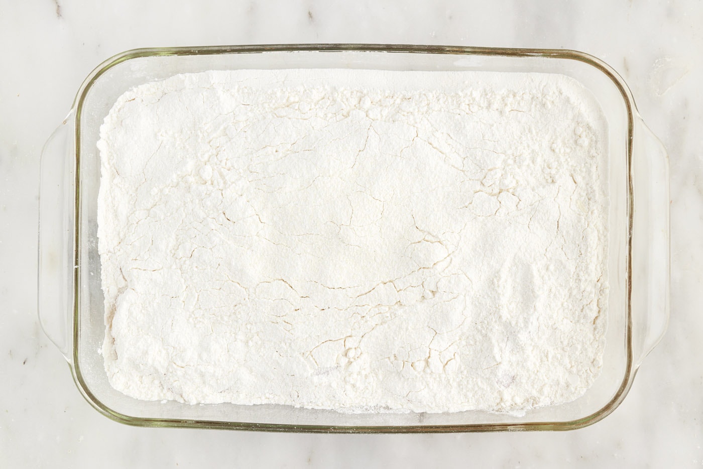 dry cake mix spread over apple pie filling in a baking dish