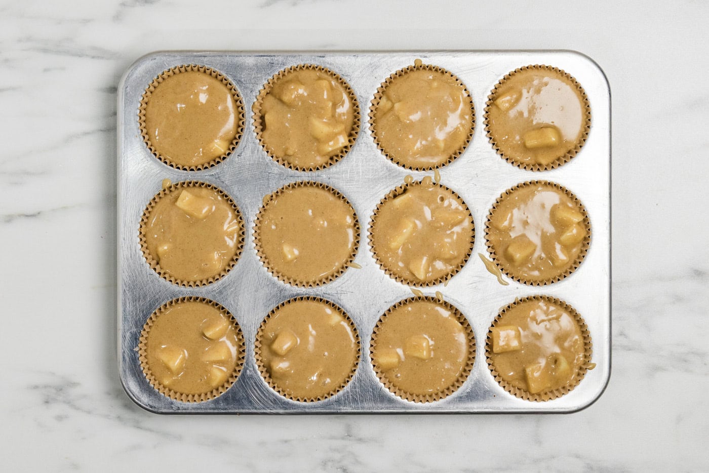 apple muffin batter in a muffin tin