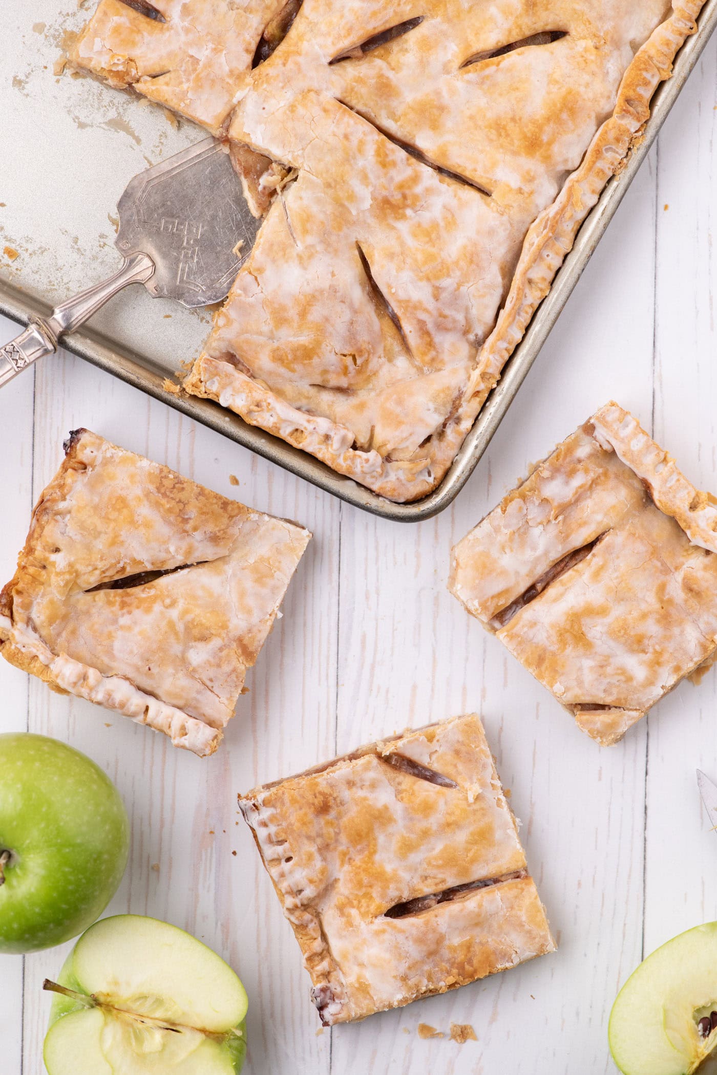 Three slices of Apple Slab Pie resting on a table with the pan in the background
