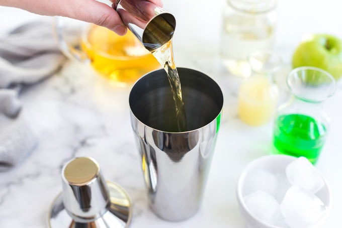 pouring apple juice into a cocktail shaker