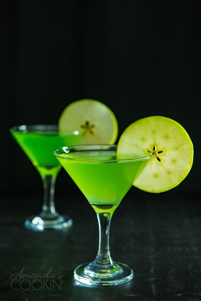 two appletini martinis on a dark background garnished with apple wheels