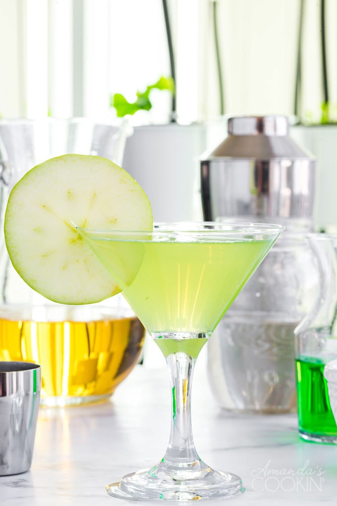 appletini in a martini glass with ingredients in the background