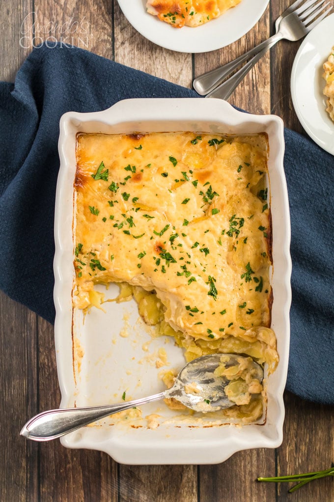 overhead shot pan of scalloped potatoes with some servings removed, spoon in pan
