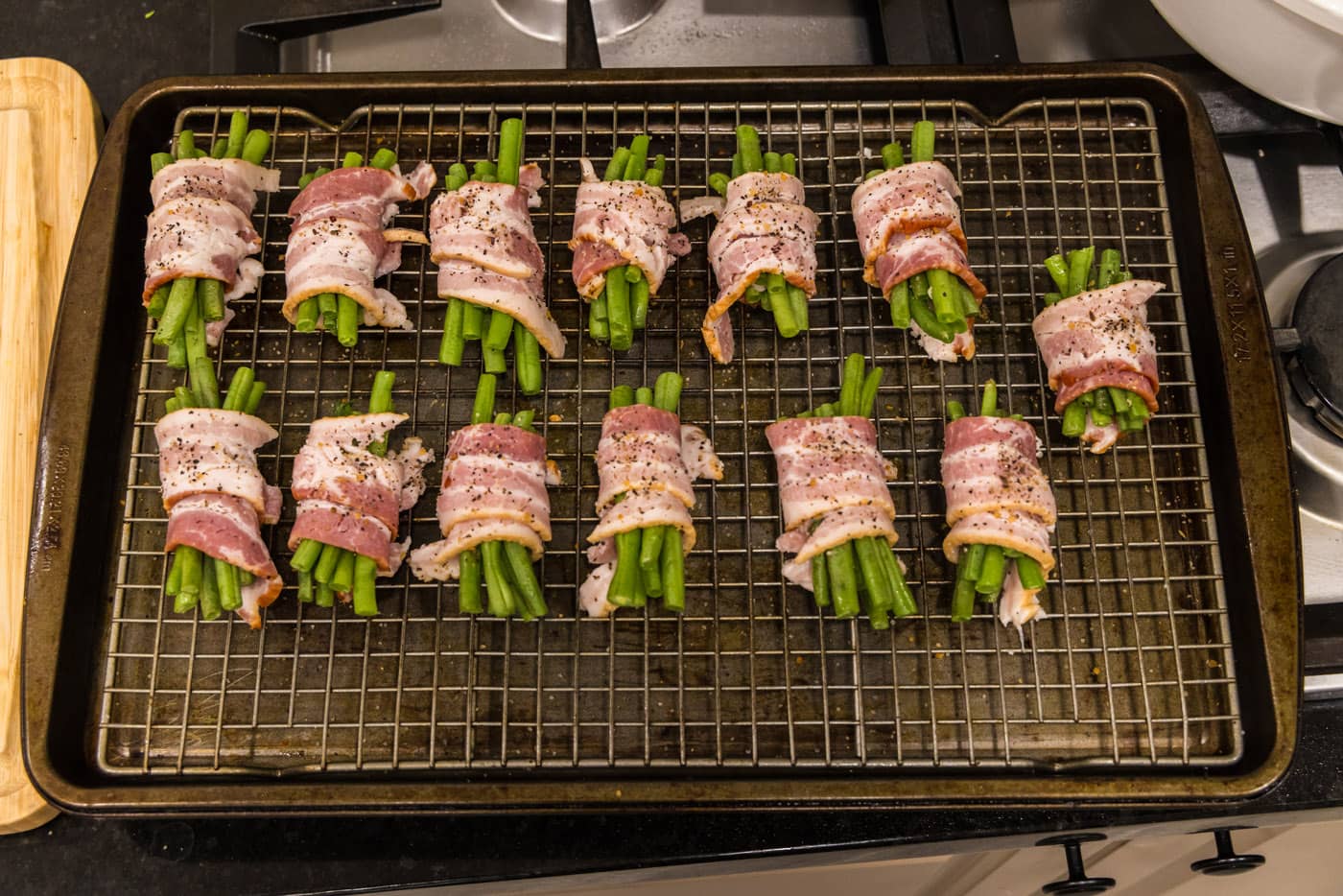 bacon wrapped green bean bundles on a baking sheet