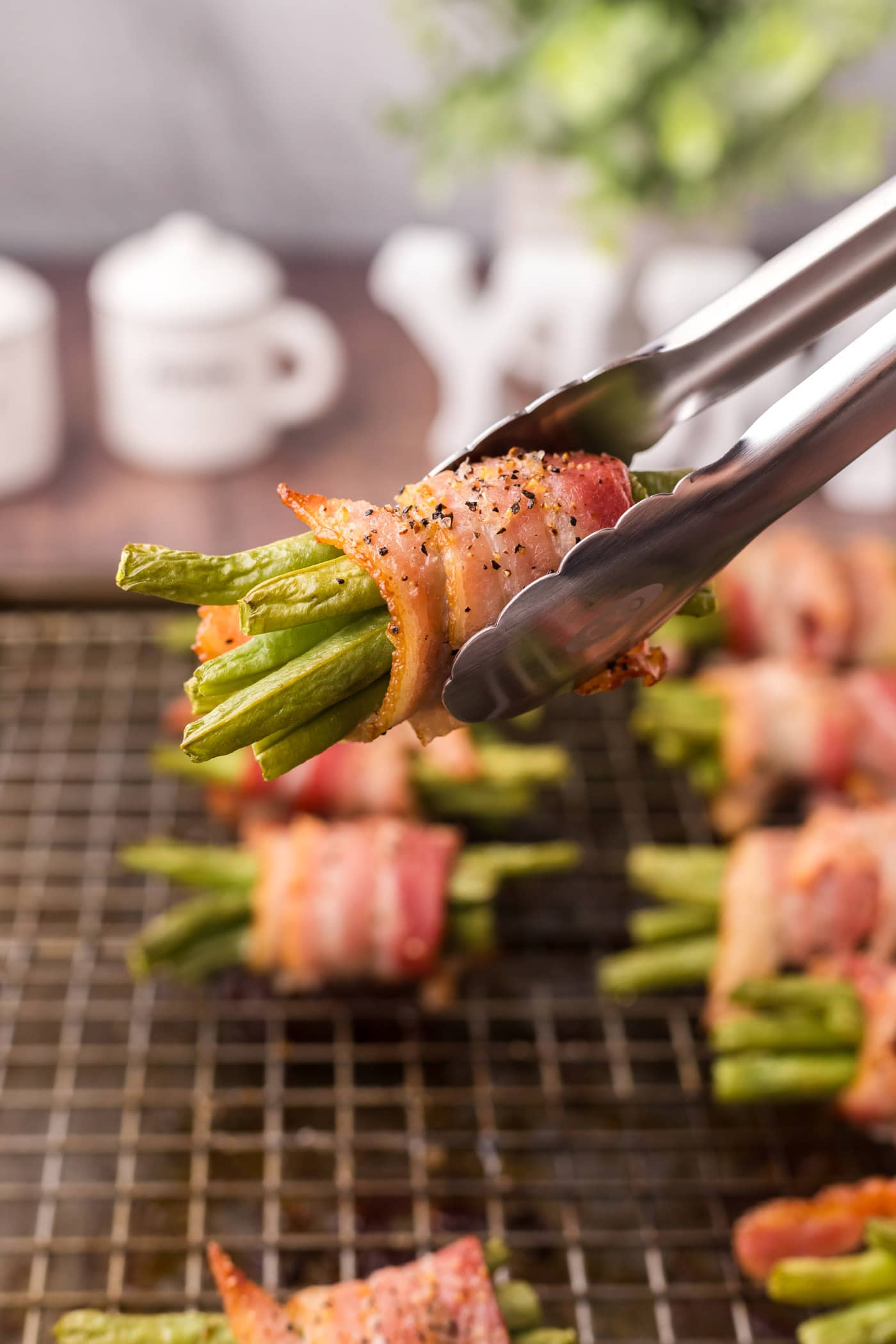 Tongs holding up Bacon Wrapped Green Beans