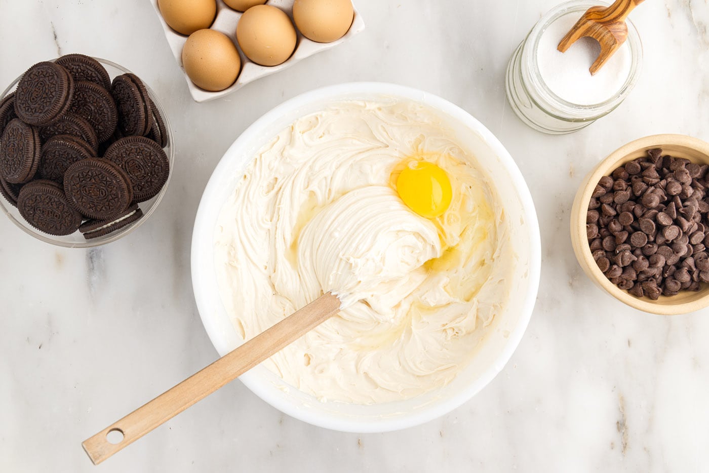 adding an egg to cheesecake batter