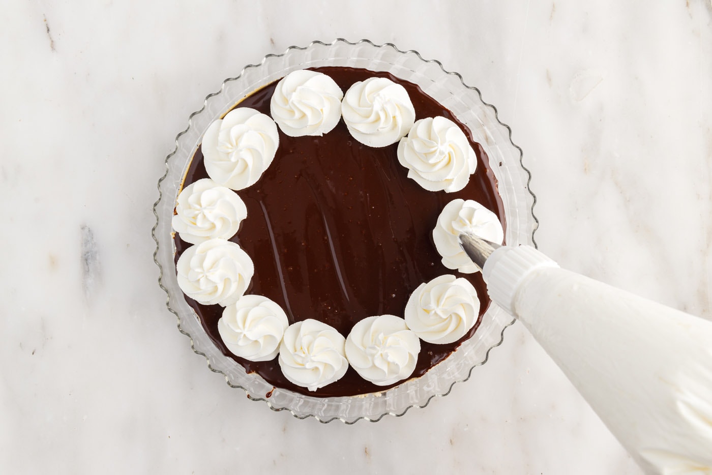 piping whipped cream onto cheesecake
