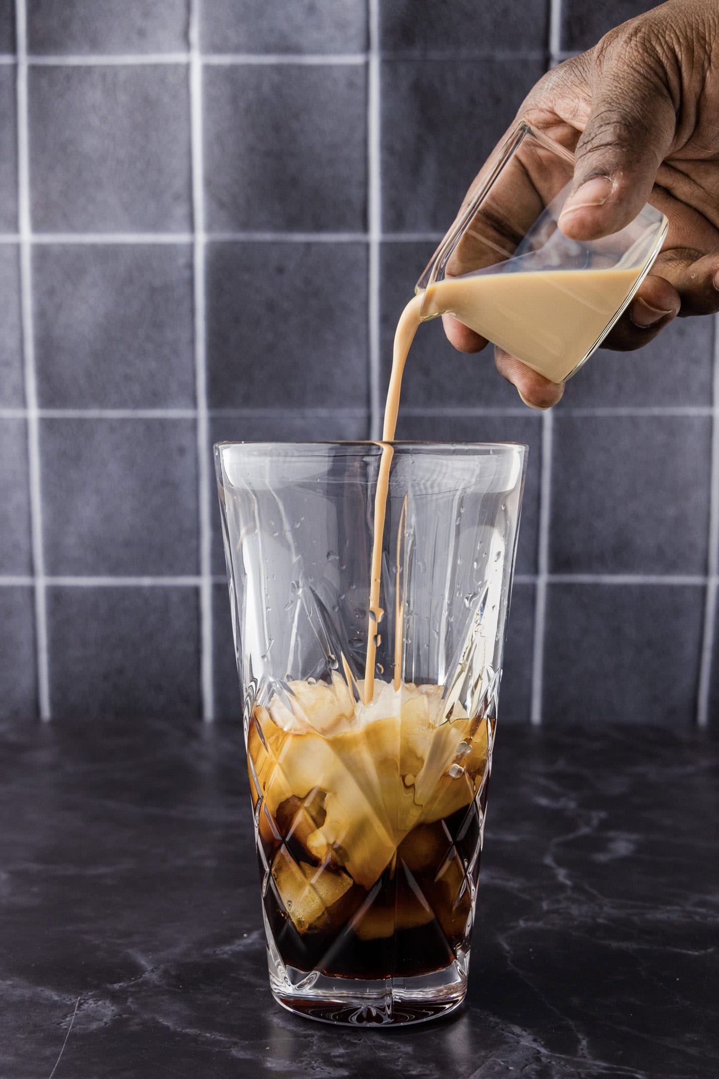 Hand pouring vodka into a cocktail shaker with Baileys and chocolate liqueur
