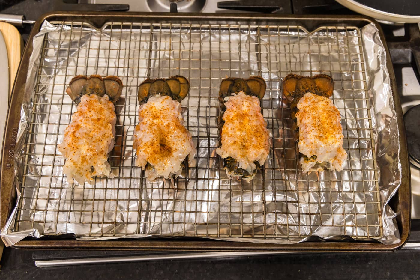 Old bay seasoned crowned lobster tails on a baking sheet