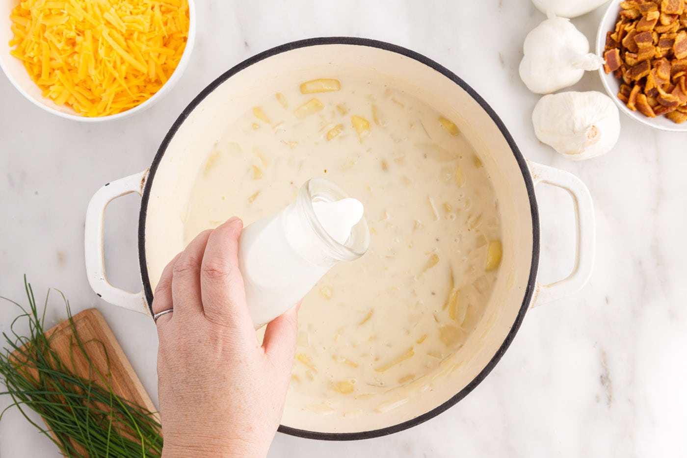 pouring heavy cream into baked potato soup