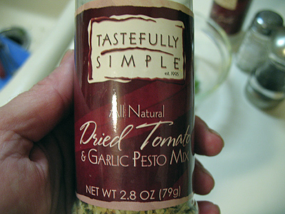 A close up photo of a bottle of dried tomato and garlic pesto mix.