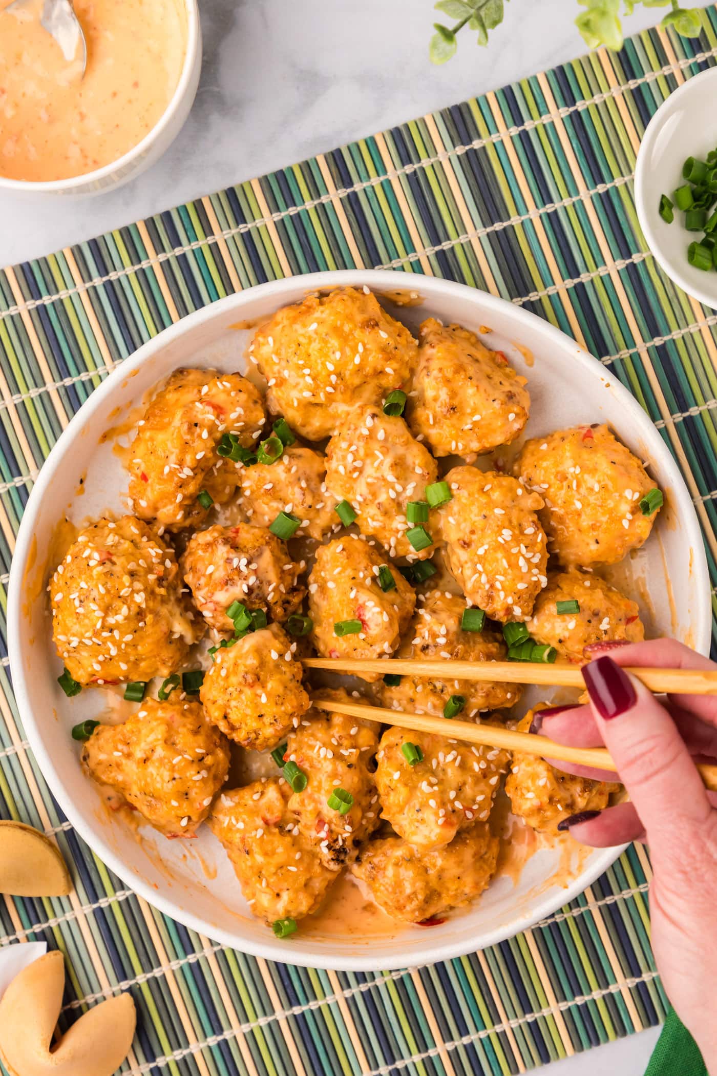 Chopsticks grabbing a piece of Bang Bang Cauliflower off a plate