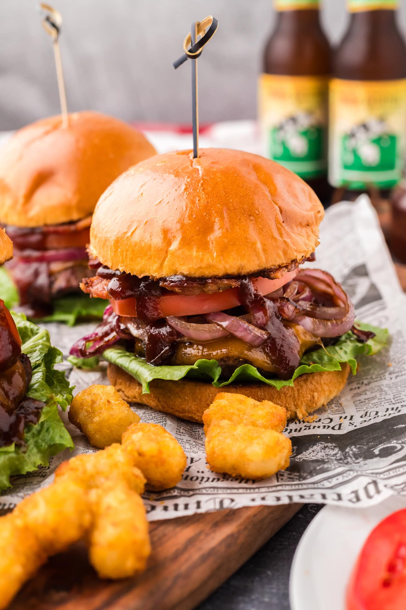 BBQ Bacon Burgers on a wooden board with tater tots