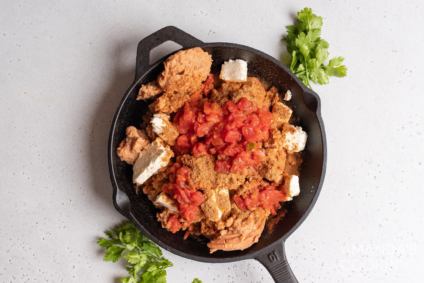 refried beans, tomatoes, cream cheese, and taco seasoning in a skillet