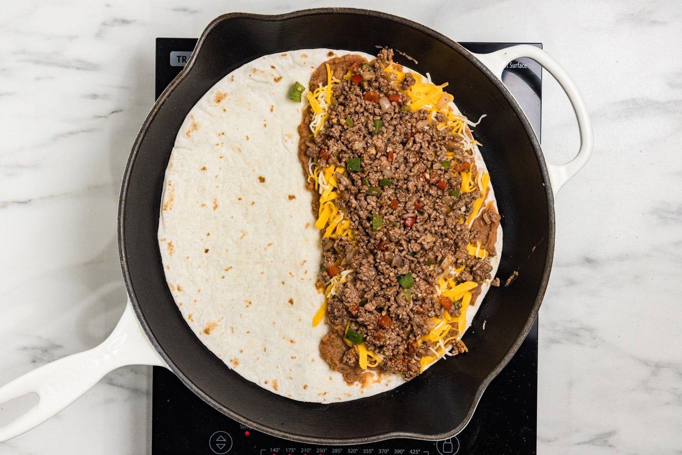 beans, cheese, and ground beef on tortilla
