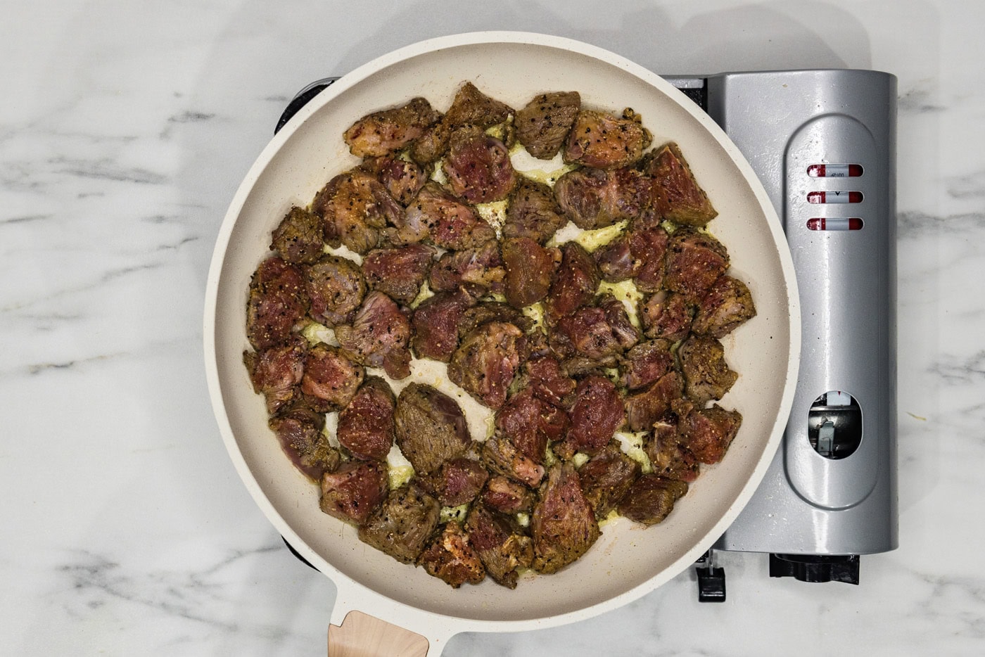 beef cubes cooking in a skillet