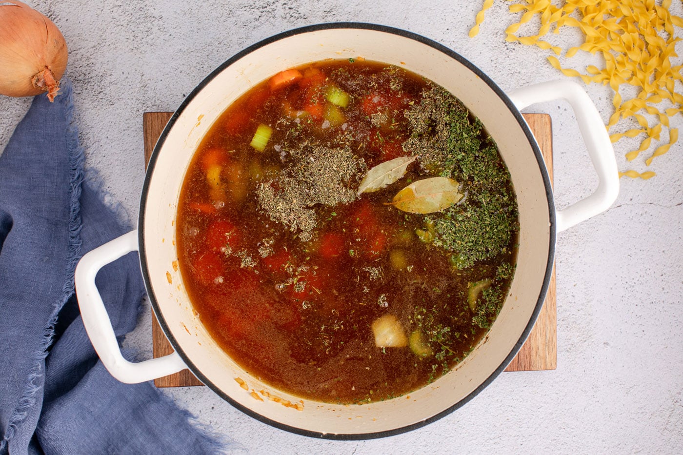 beef broth and seasonings added to veggie mix in a dutch oven