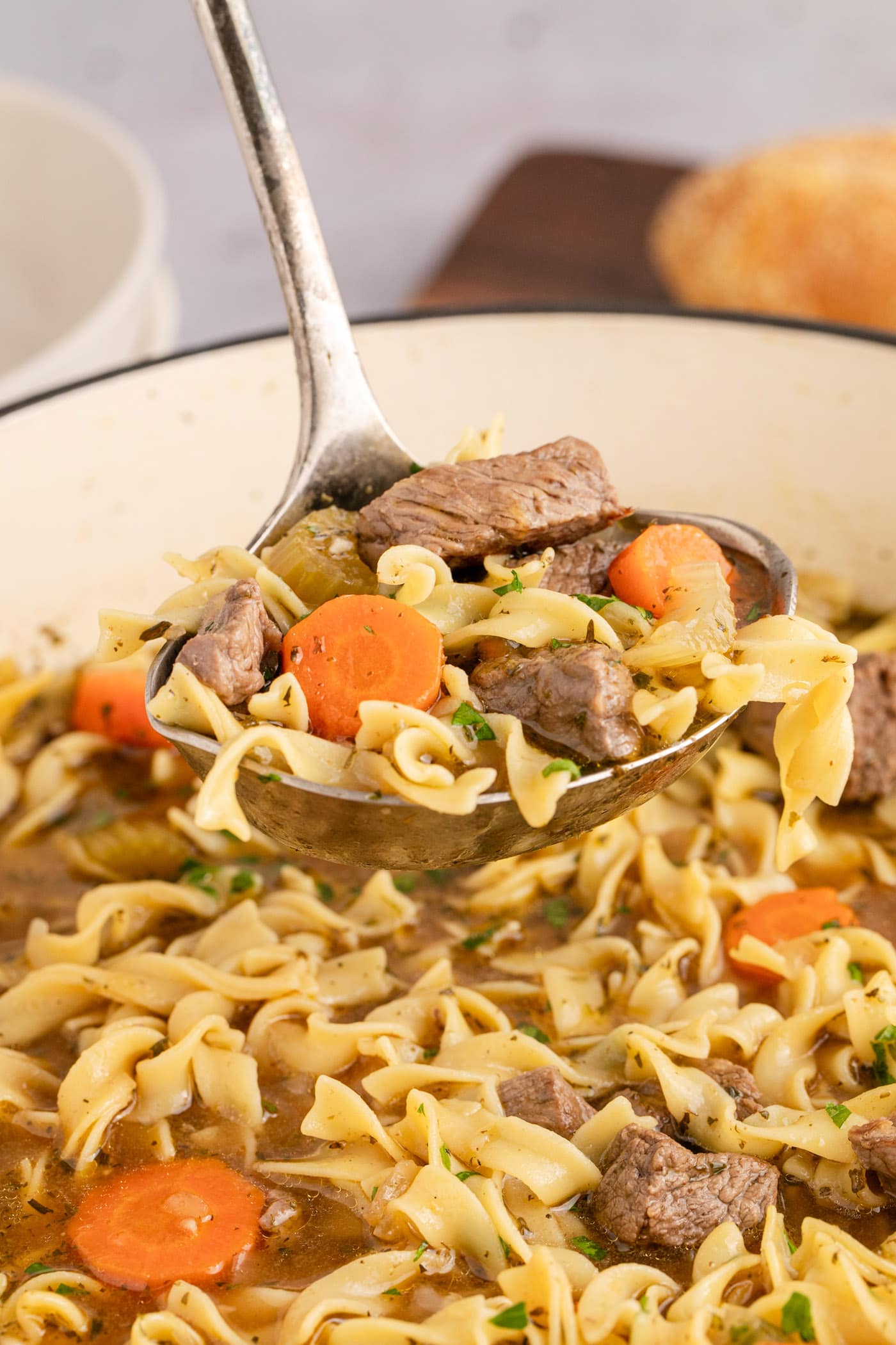 Ladle of Beef Noodle Soup held above a pot of soup