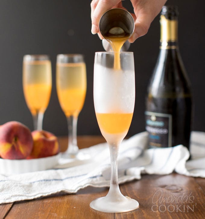 pouring peach puree into a champagne flute