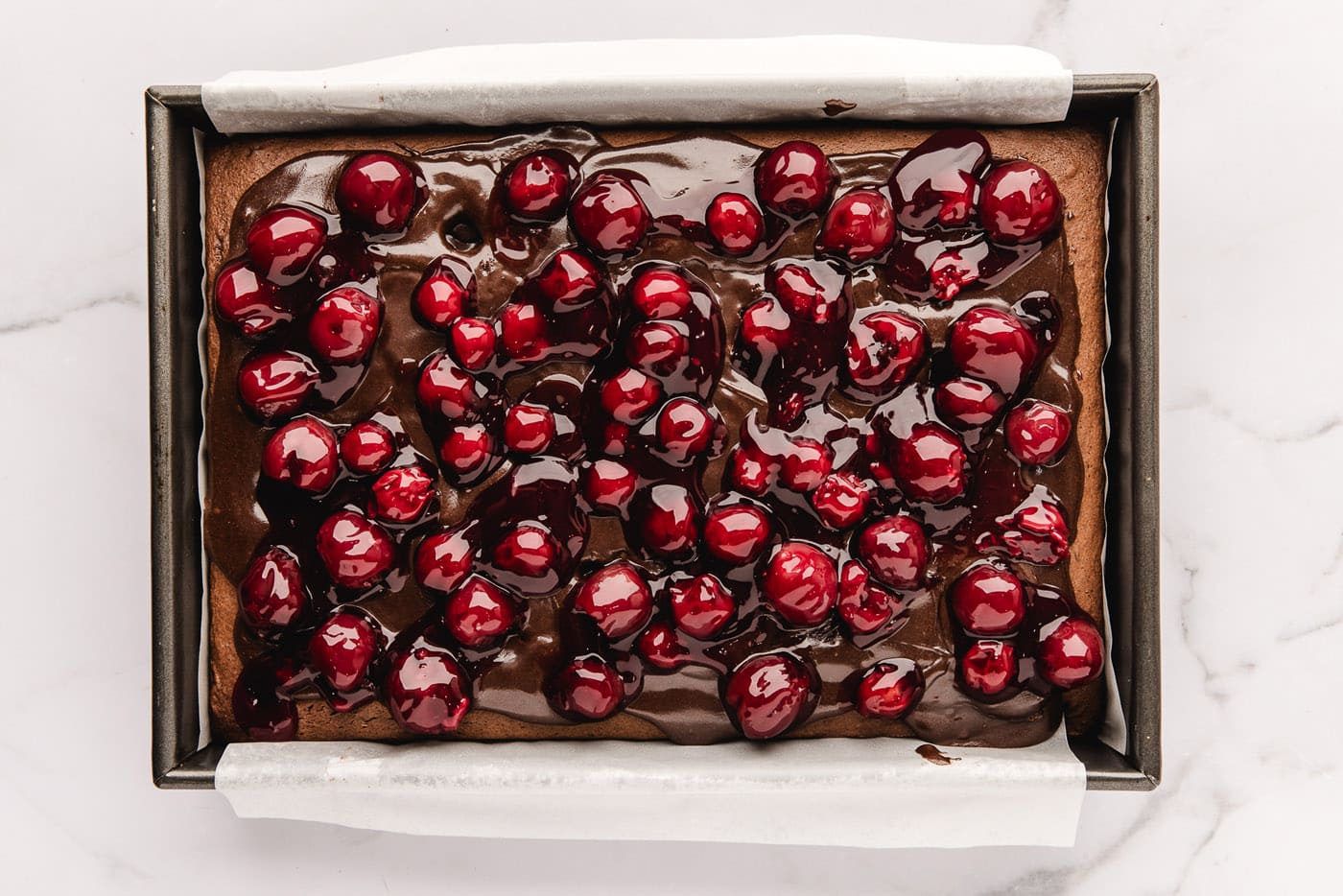 cherry pie filling added on top of fudge sauce and chocolate cake