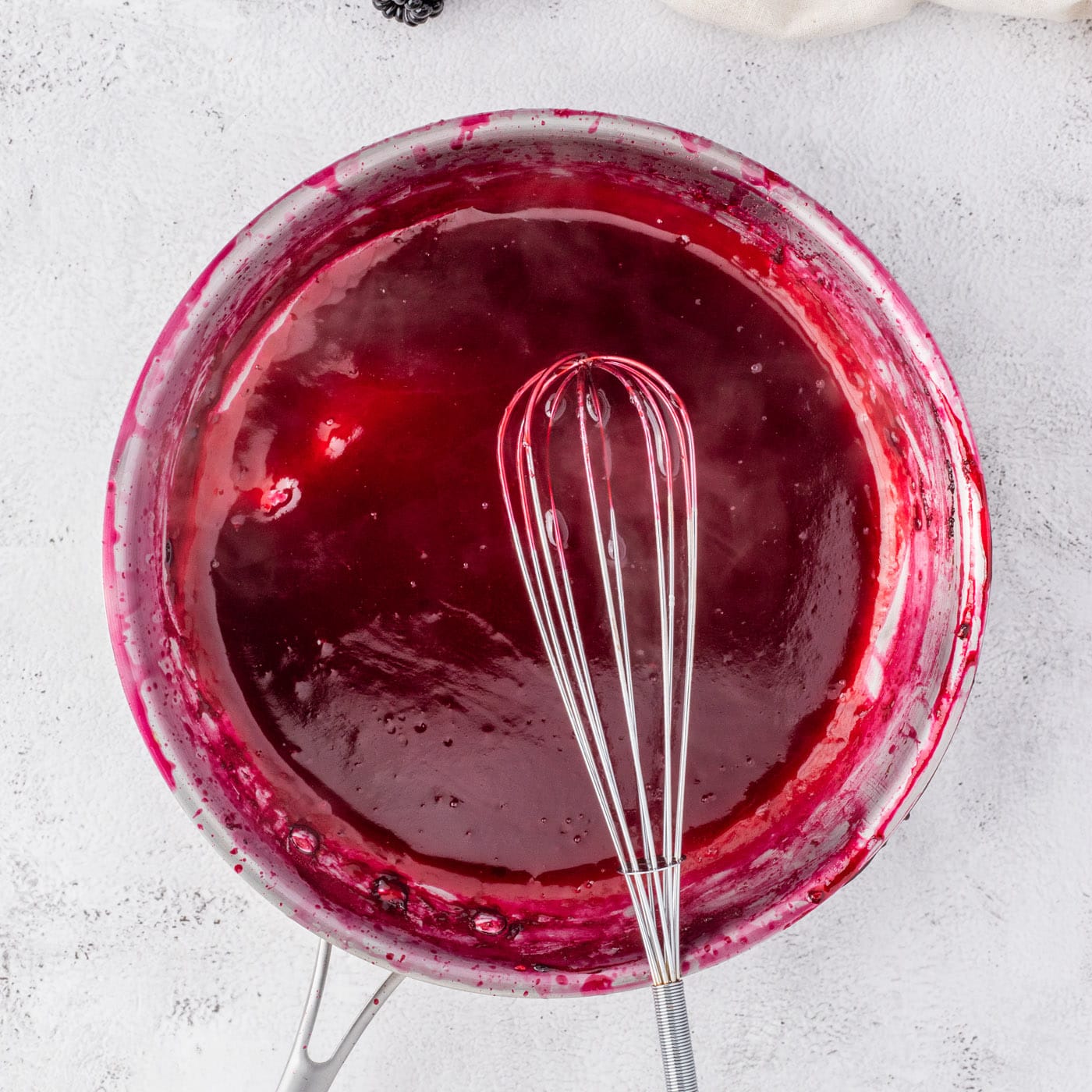 whisking blackberry reduction in a bowl