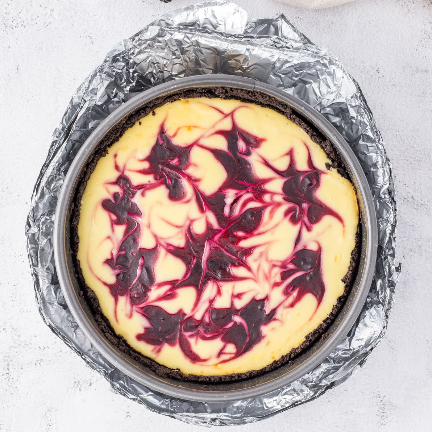 baked blackberry swirl cheesecake wrapped in aluminum foil