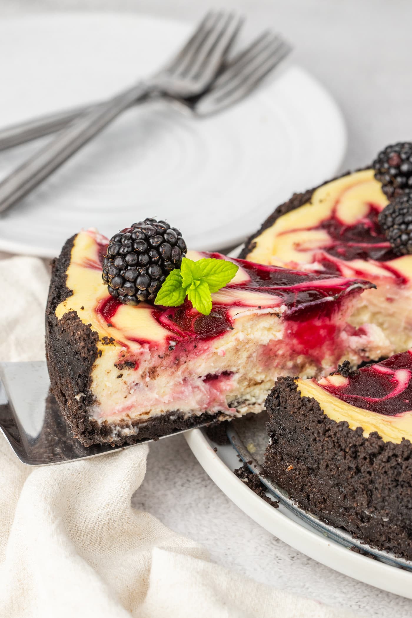 Slice of Blackberry Swirl Cheesecake being lifted away from the whole cheesecake