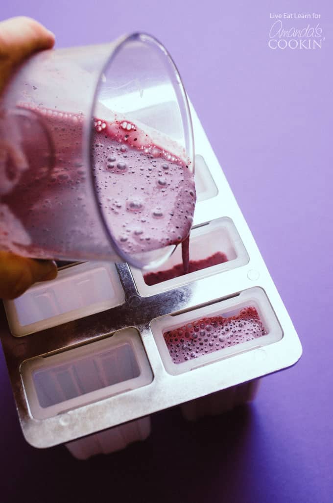 pouring blueberry cheesecake popsicle mixture into popsicle mold