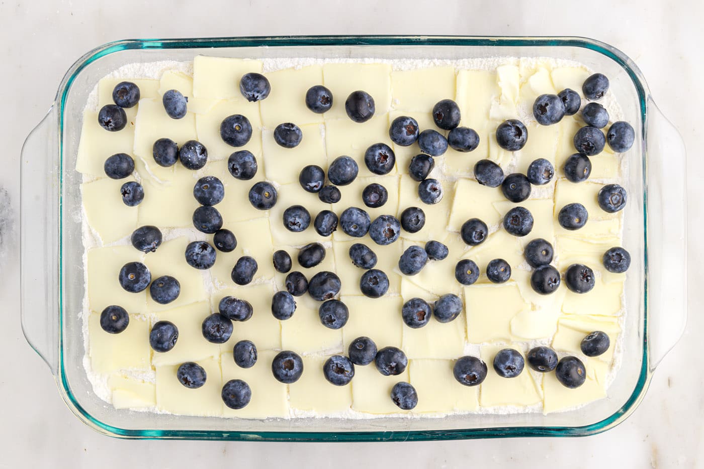 blueberry speckled on top of butter and cake mix in a baking dish