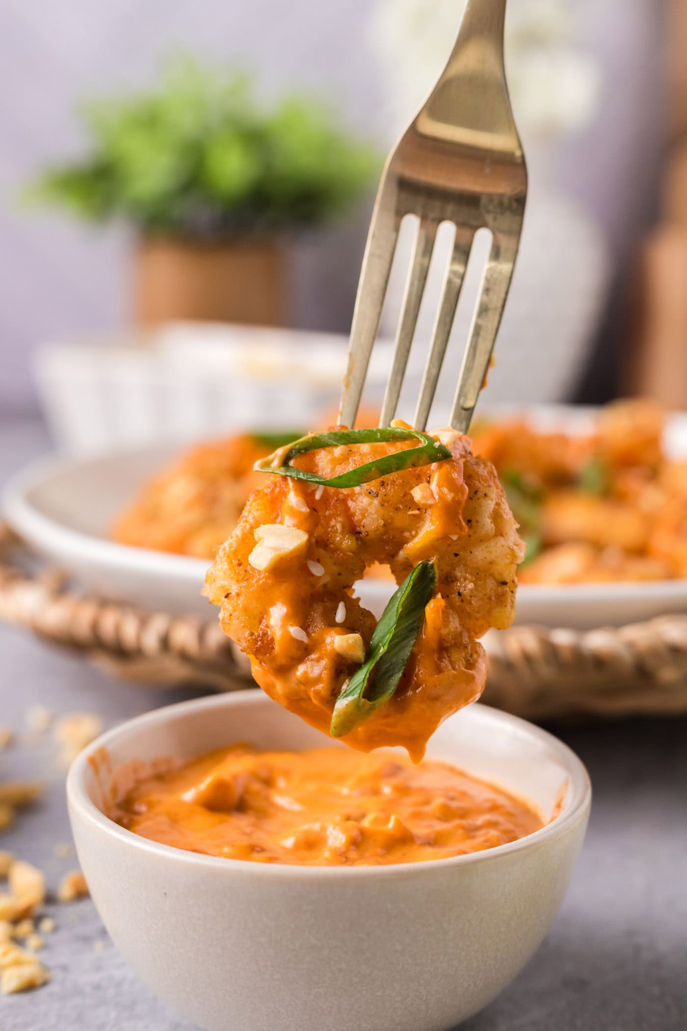 Boom Boom Shrimp on a fork held over a bowl of sauce