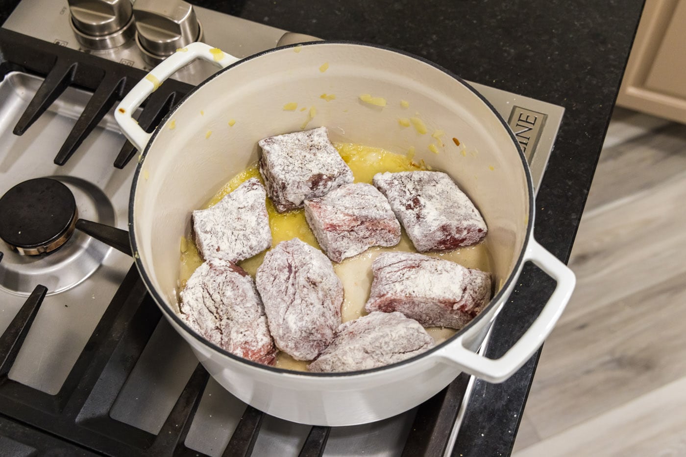 flour dredged beef short ribs searing in a dutch oven