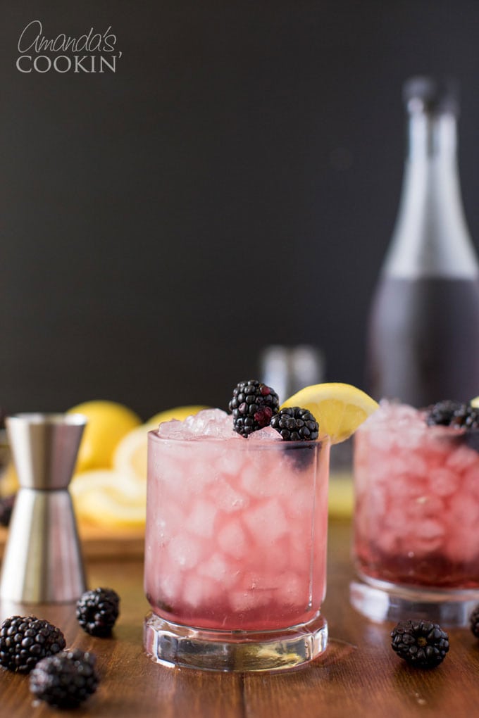 glass of bramble cocktail with blackberry and lemon garnish