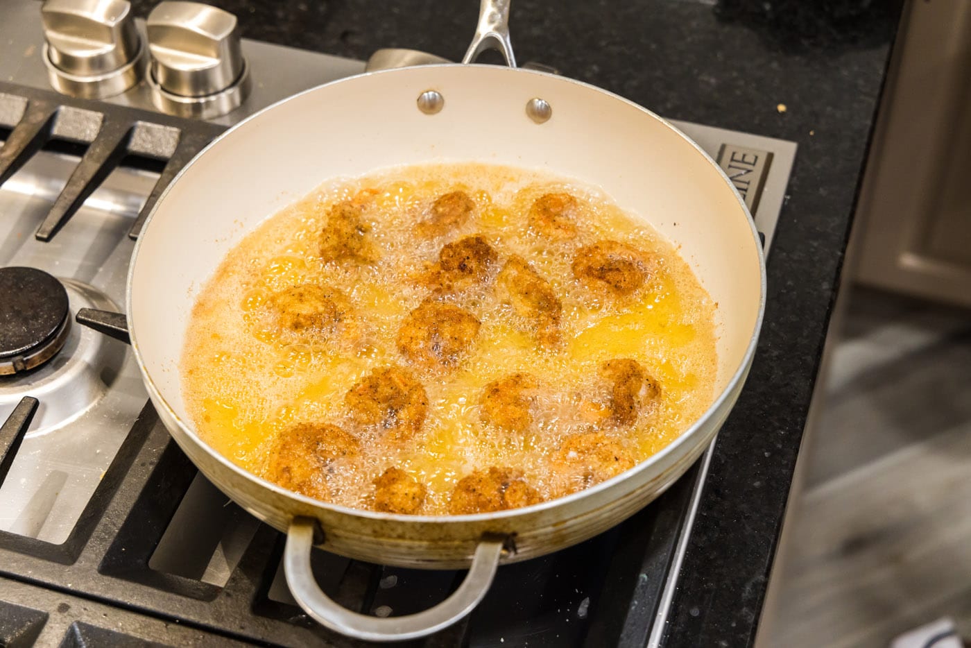 breaded shrimp cooking in oil in a skillet