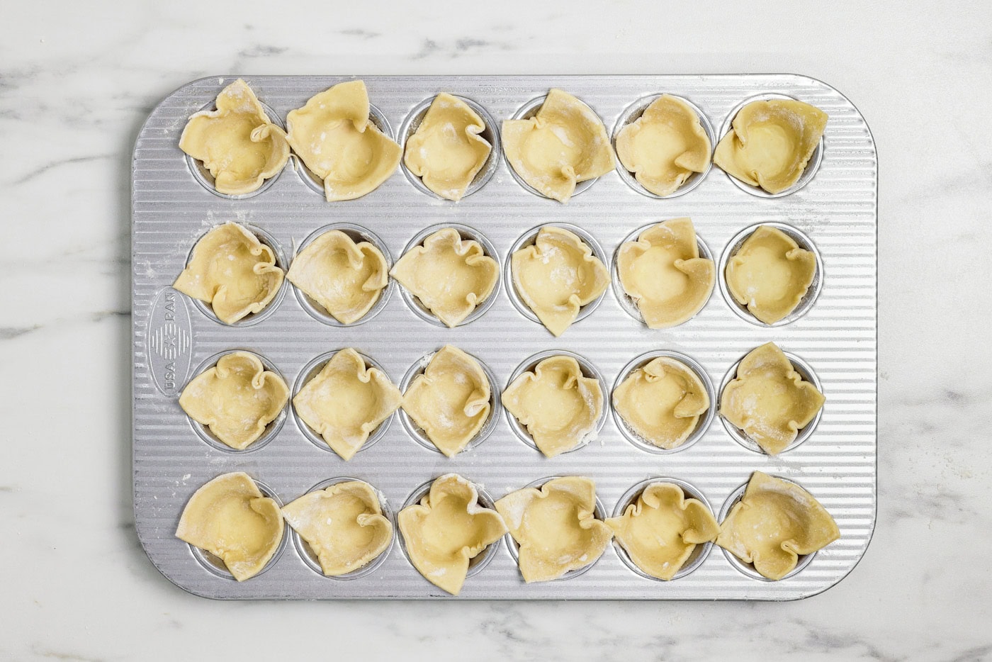 puff pastry squares tucked inside cavities on a mini muffin tin
