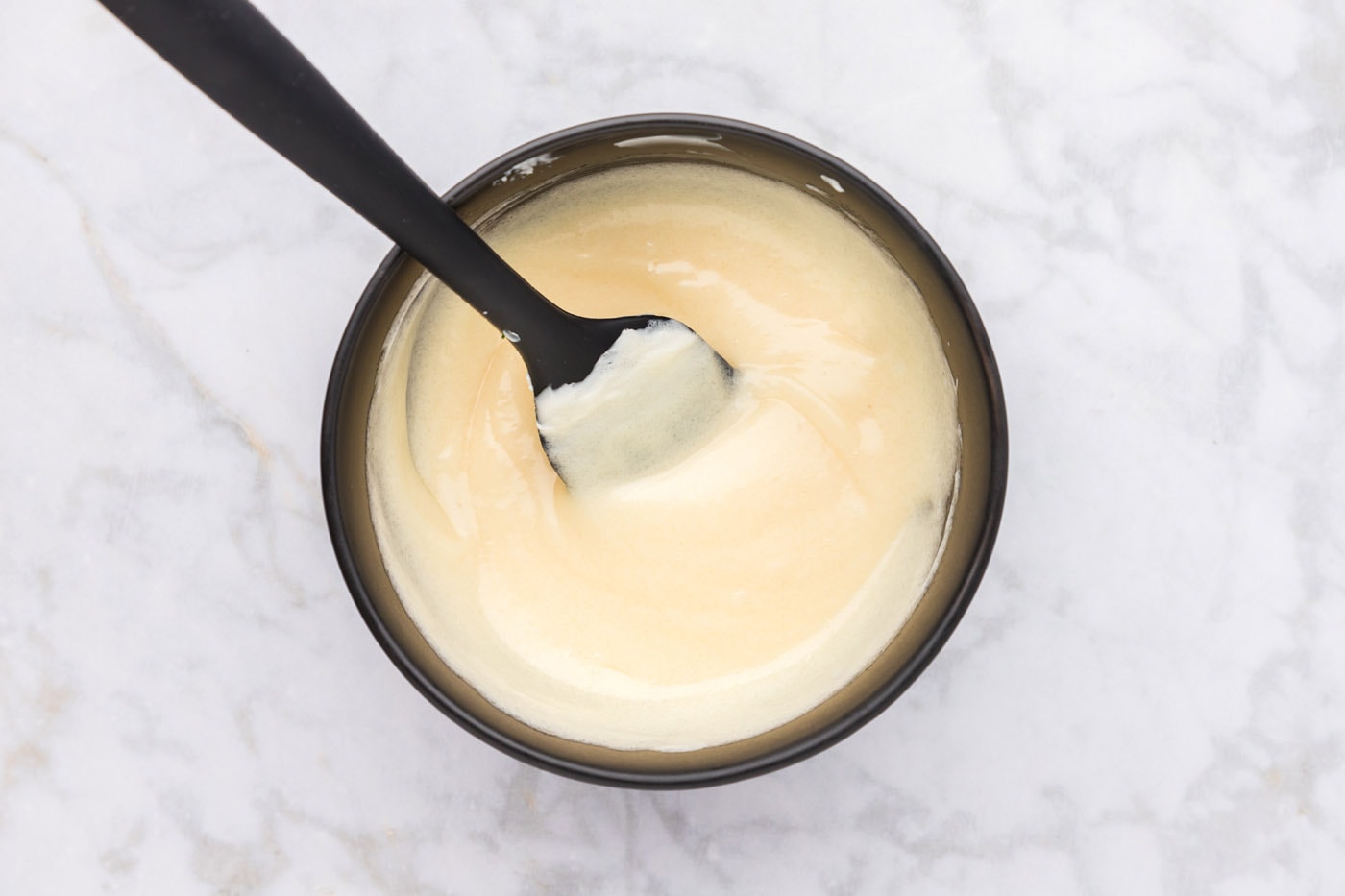 mayo dressing mixed in a bowl with a rubber spatula