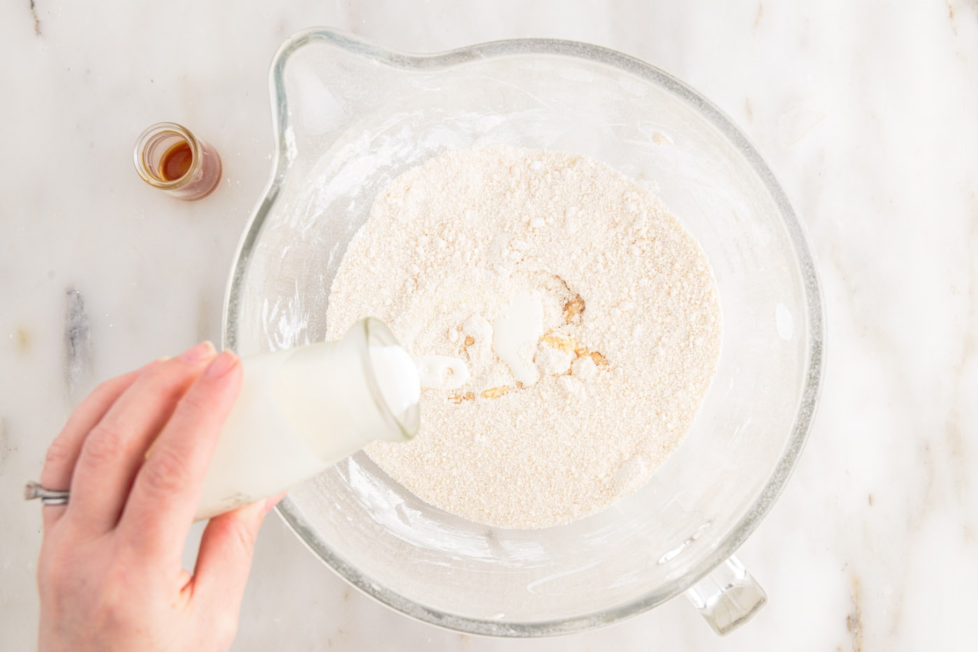 pouring heavy whipping cream to bowl of whipped brown butter and powdered sugar