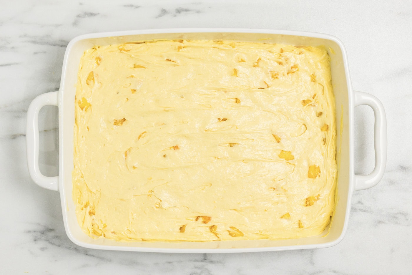 peach cake batter in a baking dish
