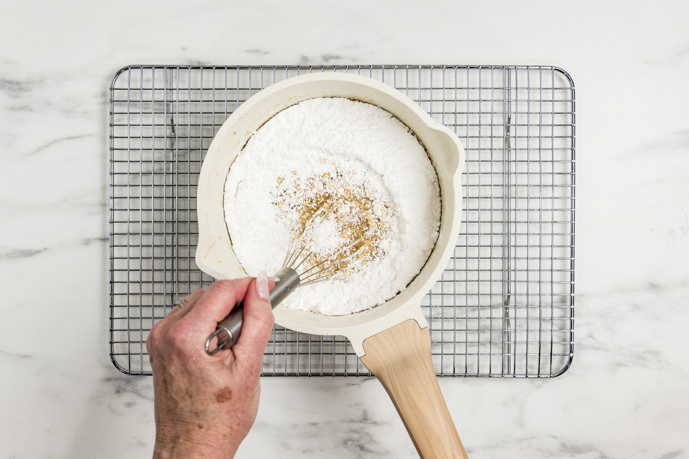 whisking powdered sugar in a saucepan of caramel icing