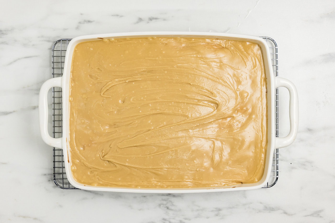 caramel icing spread over peach cake in a dish