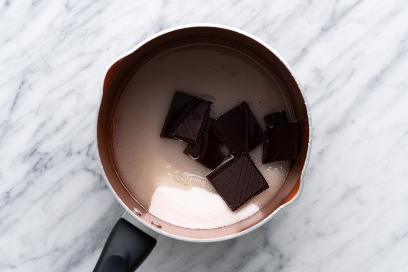sugar, water, oil, and dark chocolate in a saucepan