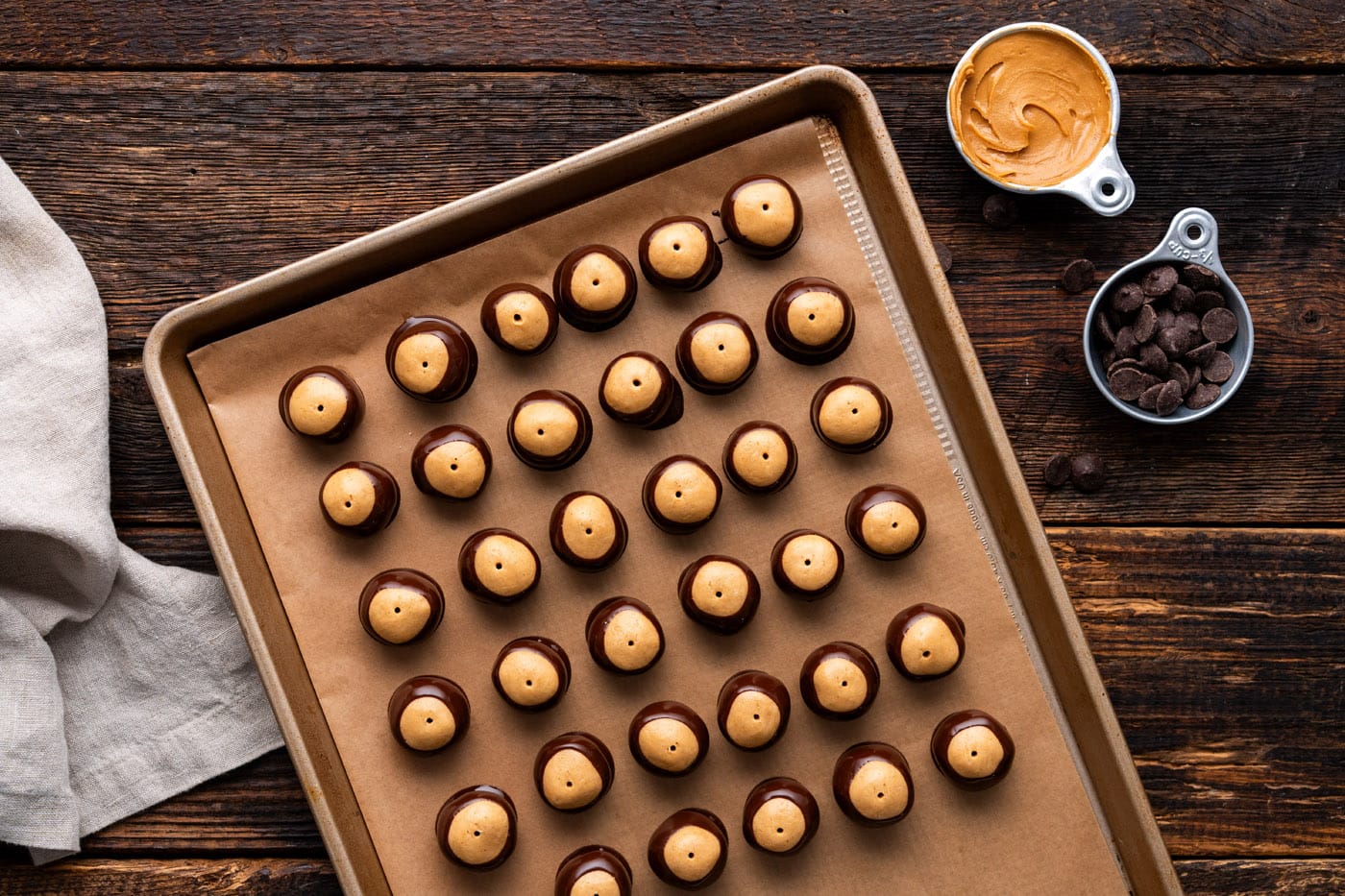 chocolate dipped buckeye candies on a baking sheet