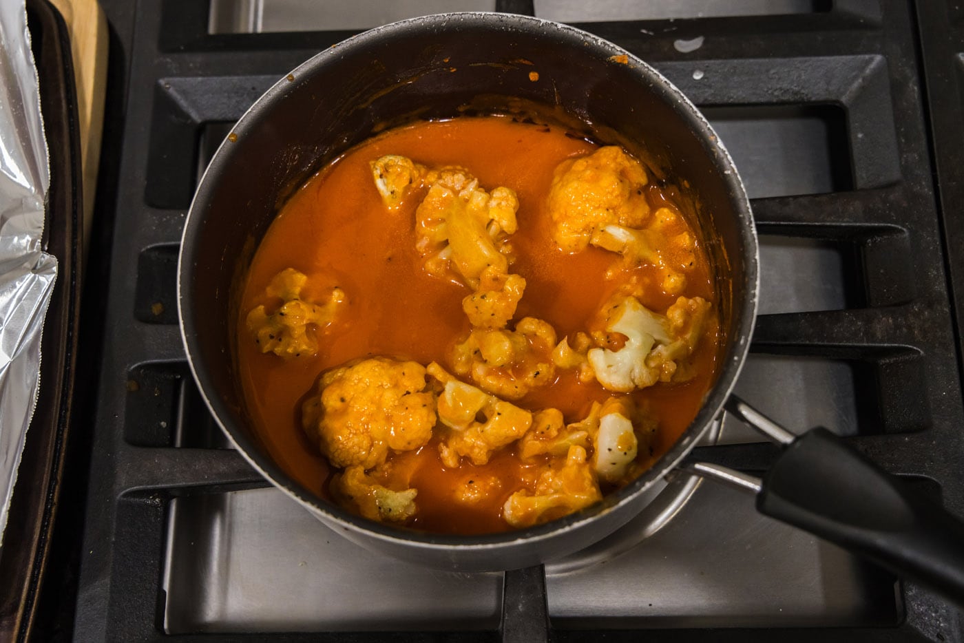 tossing cauliflower in buffalo sauce