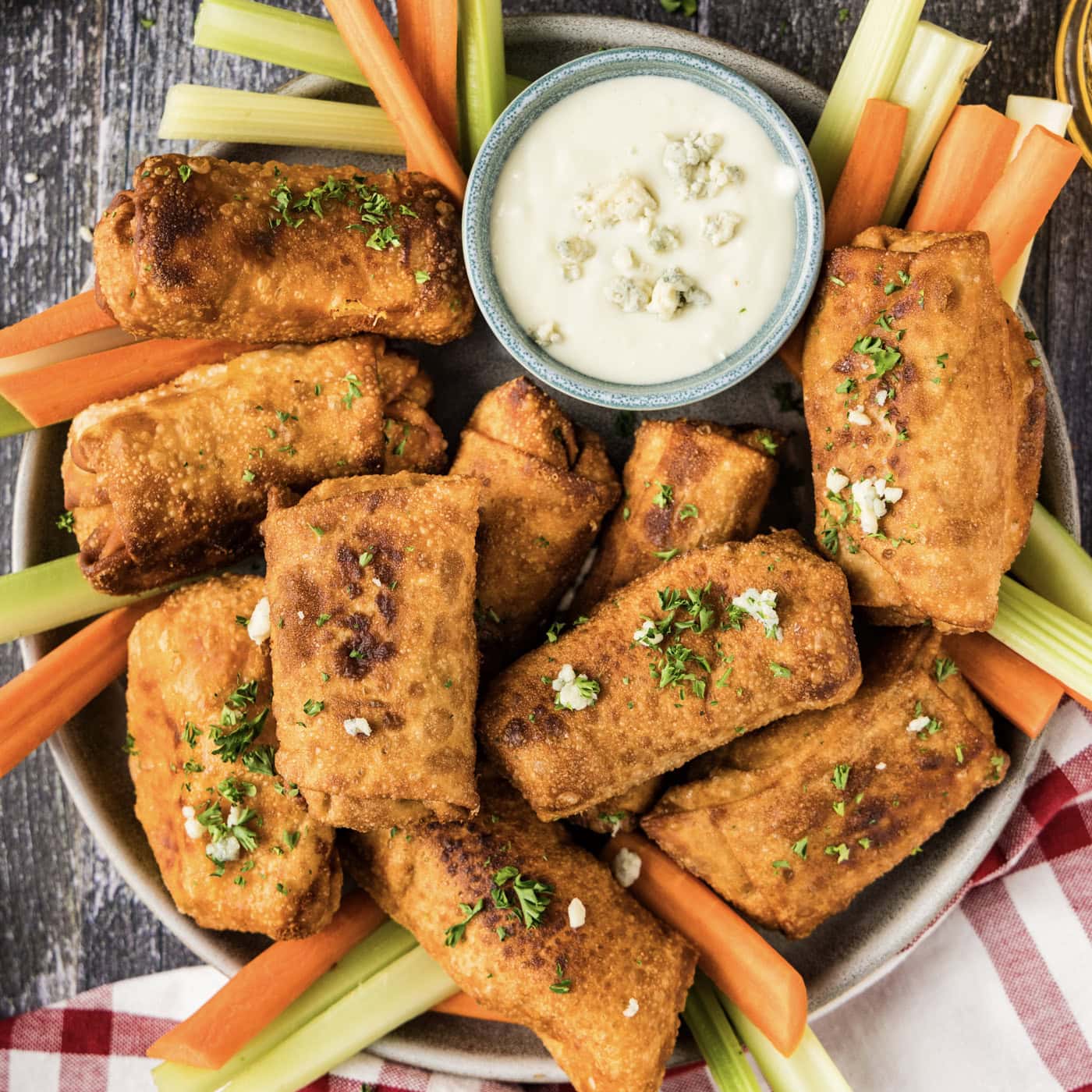 Platter of Buffalo Chicken Egg Rolls with carrots, celery and a bowl of blue cheese dressing