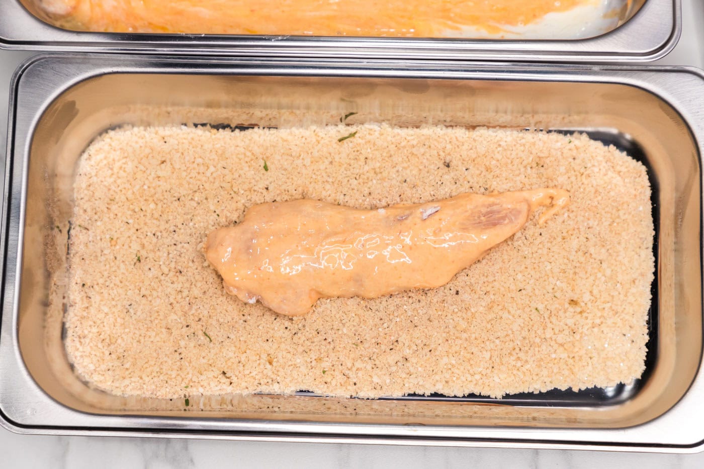 dredged buffalo chicken added to pan of breadcrumb mixture