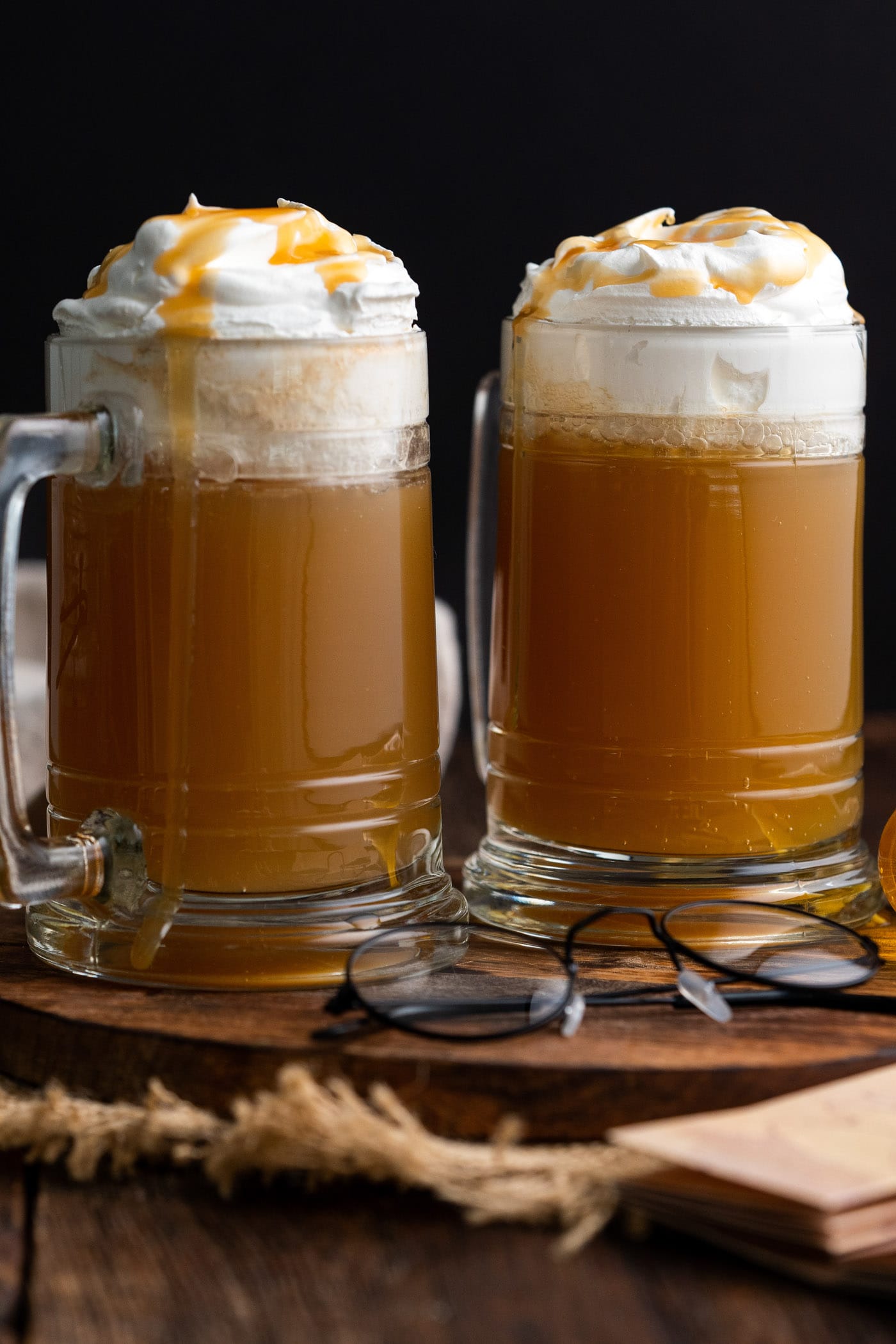 Two glasses of Butterbeer topped with whipped cream and butterscotch syrup