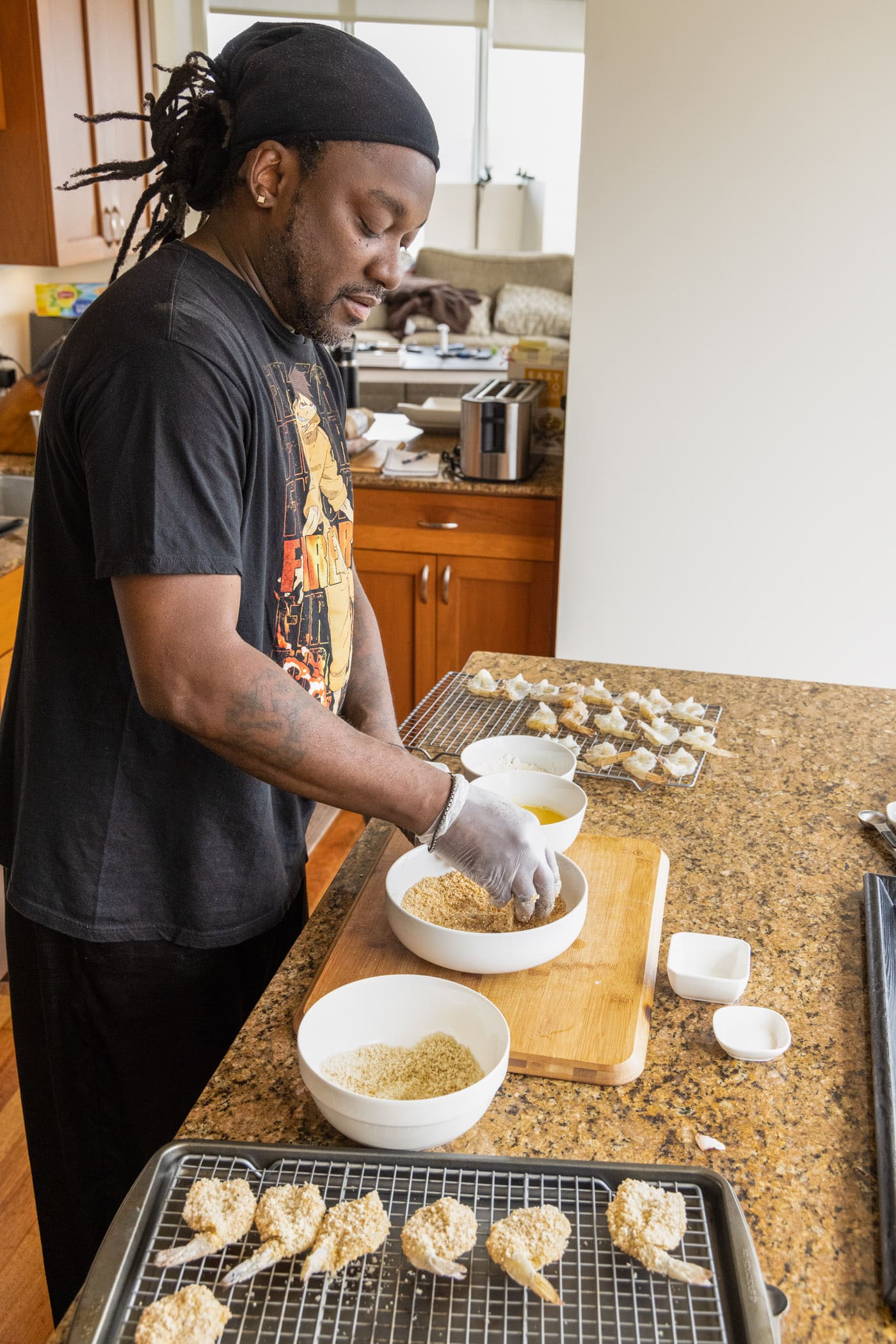 man dredging shrimp in breadcrumbs and eggs