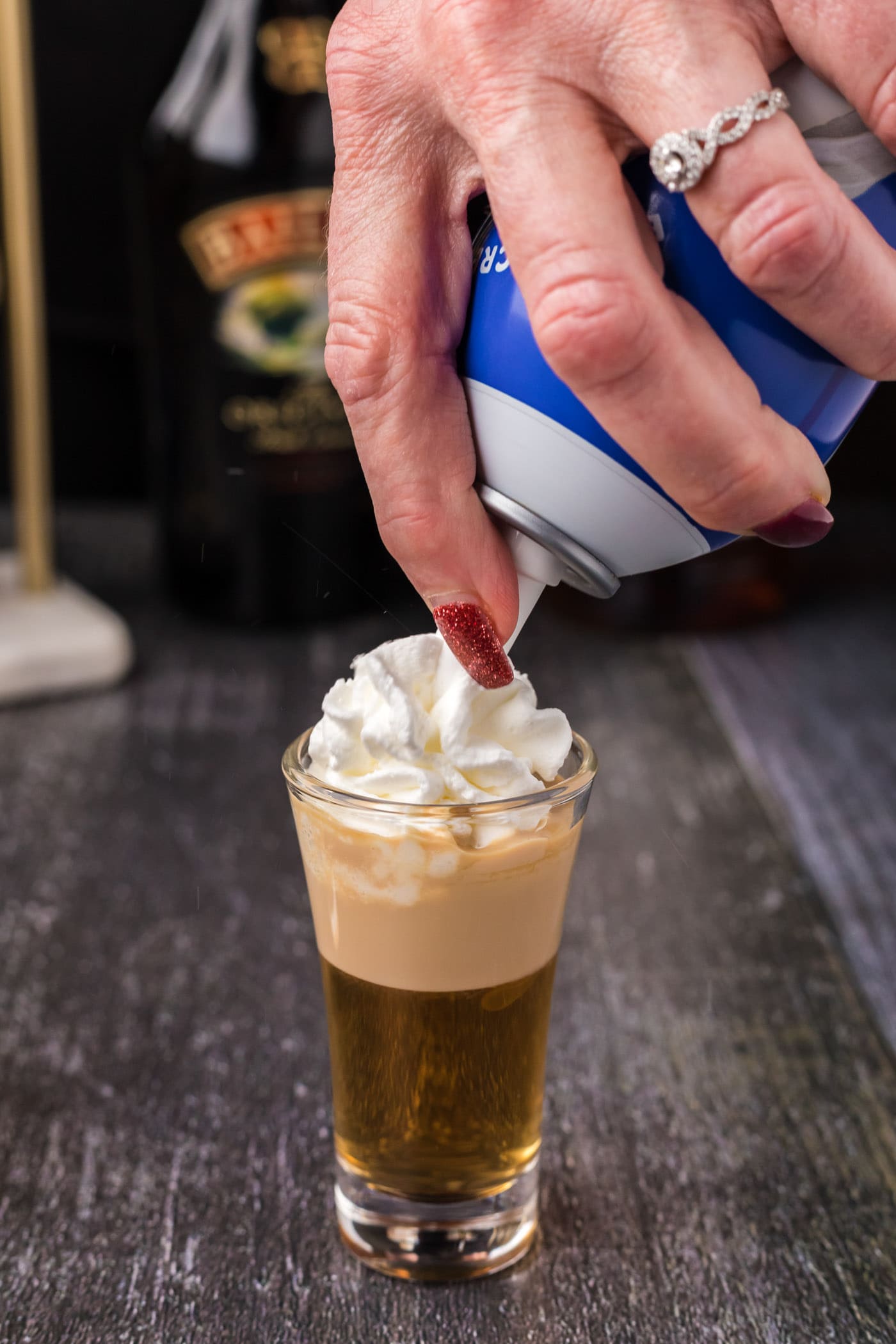 adding whipped cream over buttery nipple shot